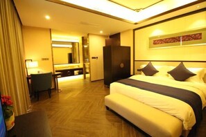Quarto de hotel com uma cama grande, uma escrivaninha, um espelho e um guarda-roupa.