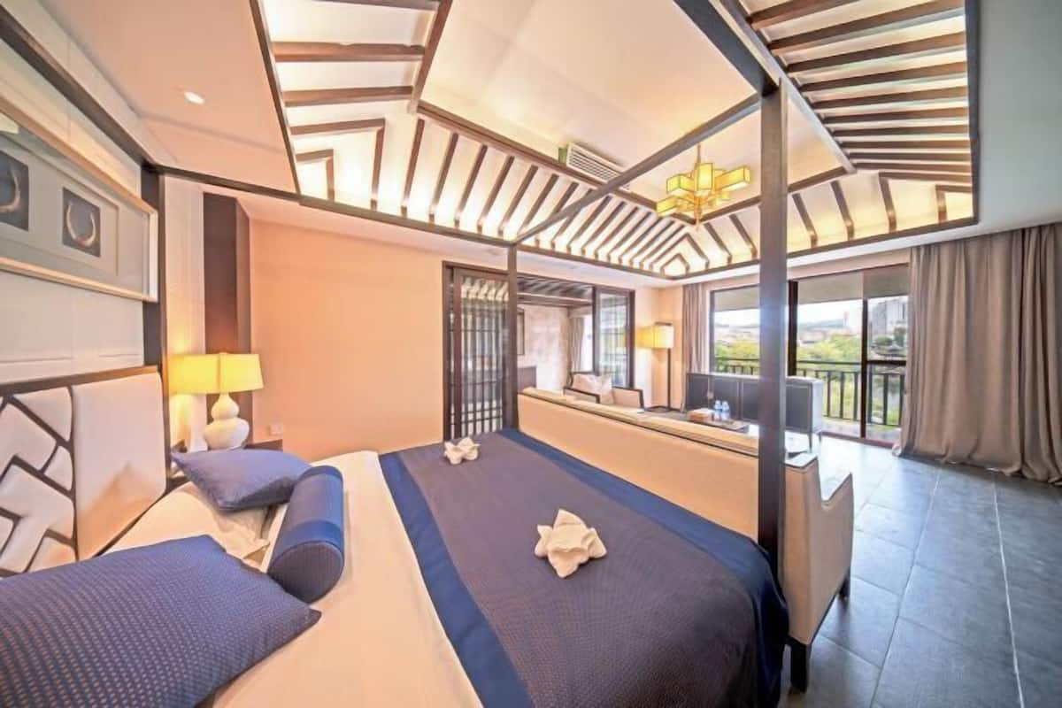 Quarto de hotel com uma cama grande, escrivaninha e varanda com vista.
