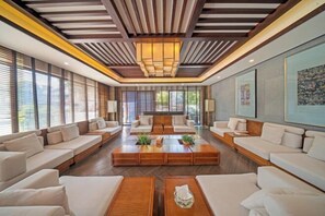 A spacious lobby with a central seating area, wooden coffee tables, and large windows allowing natural light. - Songqin Chinese Inn · Wenquan Homestay (Caotang Millennium Ancient City Tourist Area) (Weng'an County)