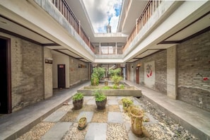 A courtyard with a central garden, multiple doors, and a high ceiling with skylights. - Songqin Chinese Inn · Wenquan Homestay (Caotang Millennium Ancient City Tourist Area) (Weng'an County)