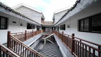 A courtyard with a central staircase connecting two buildings, each with a balcony.