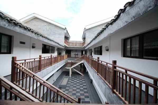 Um pátio com uma escadaria central que liga dois edifícios, cada um com uma varanda.