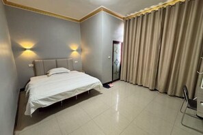 A hotel room with a bed, two wall-mounted lights, a door with a glass panel, and a curtain. - hongdu hotel (Laibin)