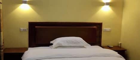 A hotel room with a wooden headboard, two bedside tables, and two wall-mounted lights.