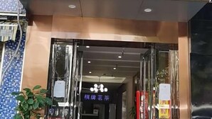 A hotel entrance with a glass door, a signboard, and a potted plant. - Jin'gutian Hotel (Wuhan)