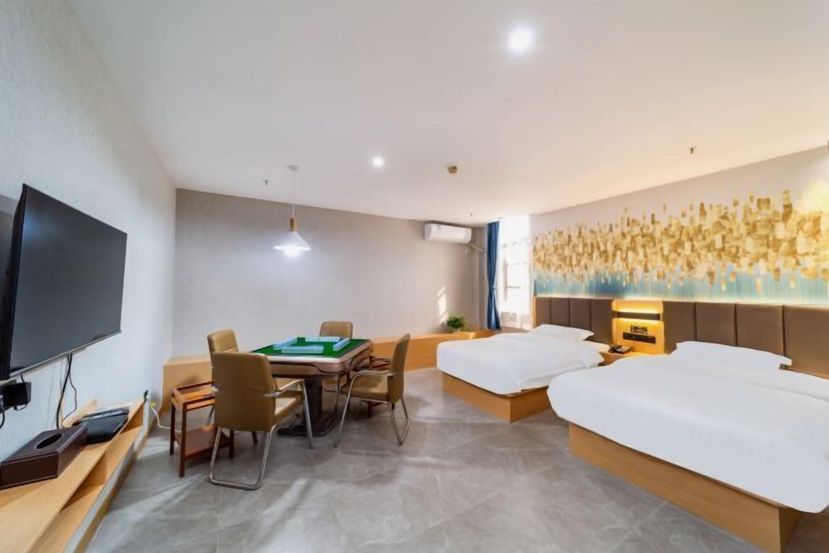 A hotel room with a bed, a desk with a computer, a television, and a wall with a decorative light feature.