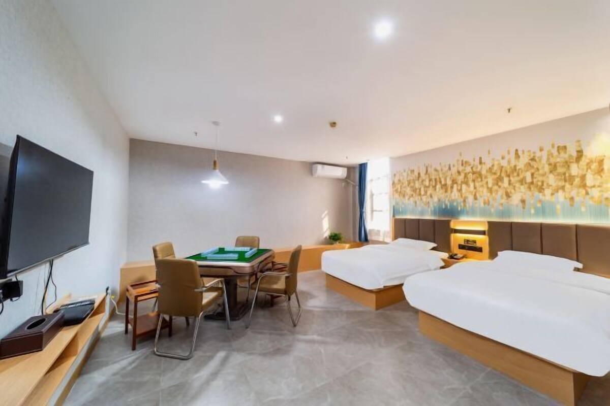 A hotel room with a bed, a desk with a computer, a television, and a wall with a decorative light feature.