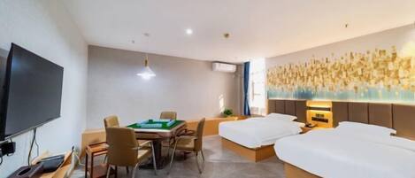 A hotel room with a bed, a desk with a computer, a television, and a wall with a decorative light feature.