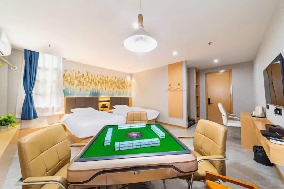 A hotel room with a green pool table, a bed with white bedding, a desk with a computer, and a large mirror on the wall.