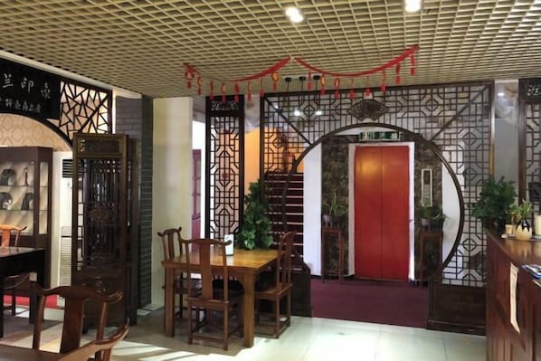 A traditional interior with a reception desk, wooden furniture, and decorative screens.