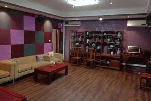 A room with a sofa, a coffee table, a TV, and a bookshelf. - China Manor Hotel & Restaurant (Colombo)