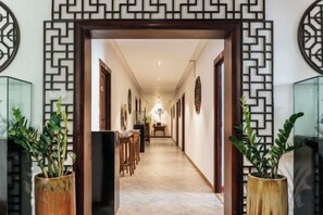 A hallway with a patterned wall design, potted plants, and a series of doors leading to rooms. - China Manor Hotel & Restaurant (Colombo)