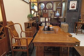 A traditional wooden dining table with chairs, surrounded by shelves with decorative items.
