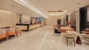 A spacious lobby with a reception desk, seating area, and a modern chandelier.