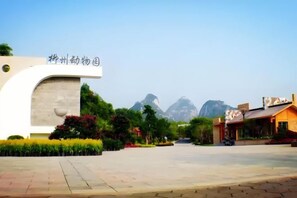 A building entrance with a sign, a paved area, and a mountain in the background.