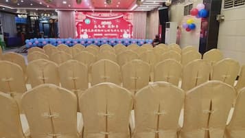 Rows of chairs with headrests, a stage with a banner, and balloons.
