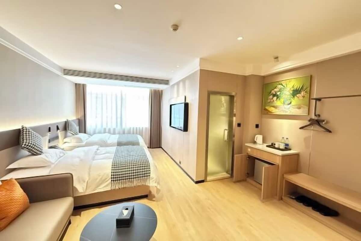 Une chambre d’hôtel avec un lit, un canapé, un bureau, une télévision et un tableau au mur.