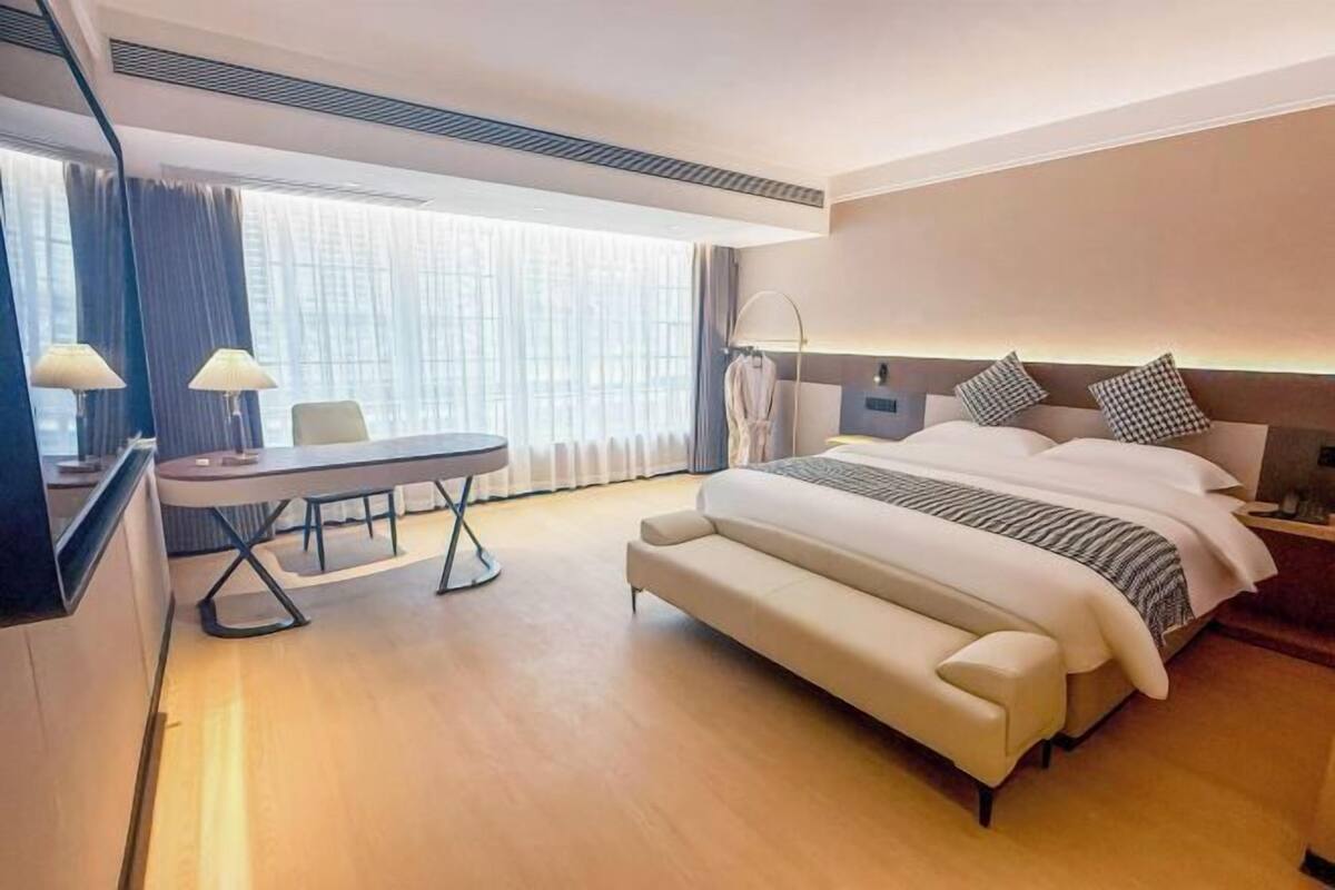 Une chambre d’hôtel moderne, dotée d’un grand lit, d’un bureau et d’une chaise.
