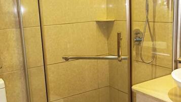 A shower area with a glass door, a towel rack, and a showerhead.