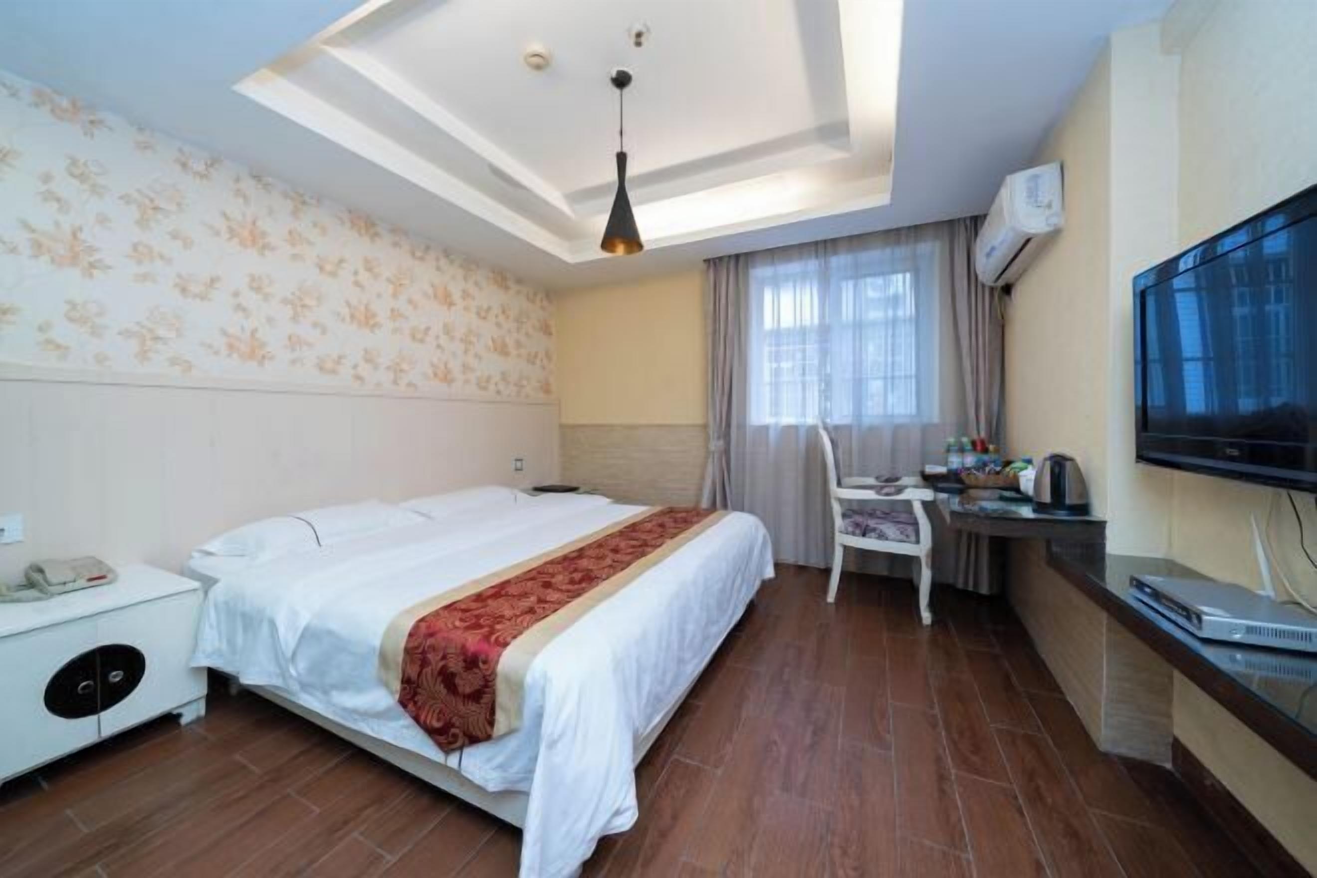 Une chambre d’hôtel équipée d’un lit, d’un bureau, d’une chaise, d’une télévision et d’un appareil de climatisation.