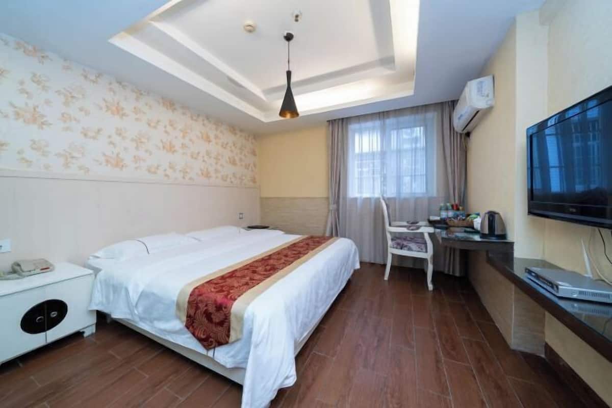 Une chambre d’hôtel équipée d’un lit, d’un bureau, d’une chaise, d’une télévision et d’un appareil de climatisation.