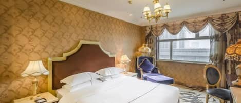 A hotel room with a large bed, a nightstand, a lamp, a chair, and a window with curtains.