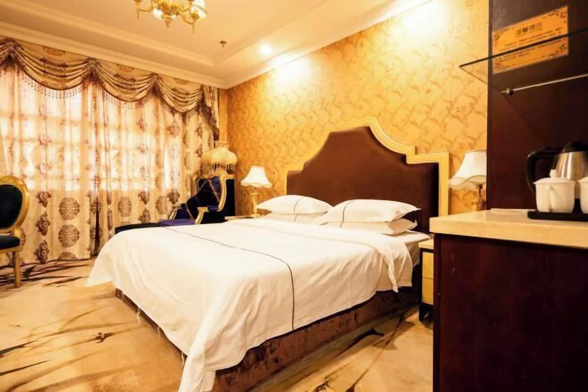 Una habitación de hotel con una cama grande, dos mesitas de noche, un escritorio y una silla.