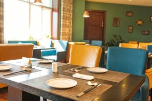 Ein Restaurant mit gedeckten Tischen, Stühlen und Blick ins Innere.