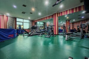 Een sportschool met diverse fitnessapparaten, een grote spiegel en een groene vloer.
