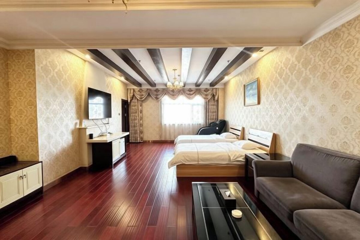 A hotel room with a bed, a sofa, a TV, and a desk.