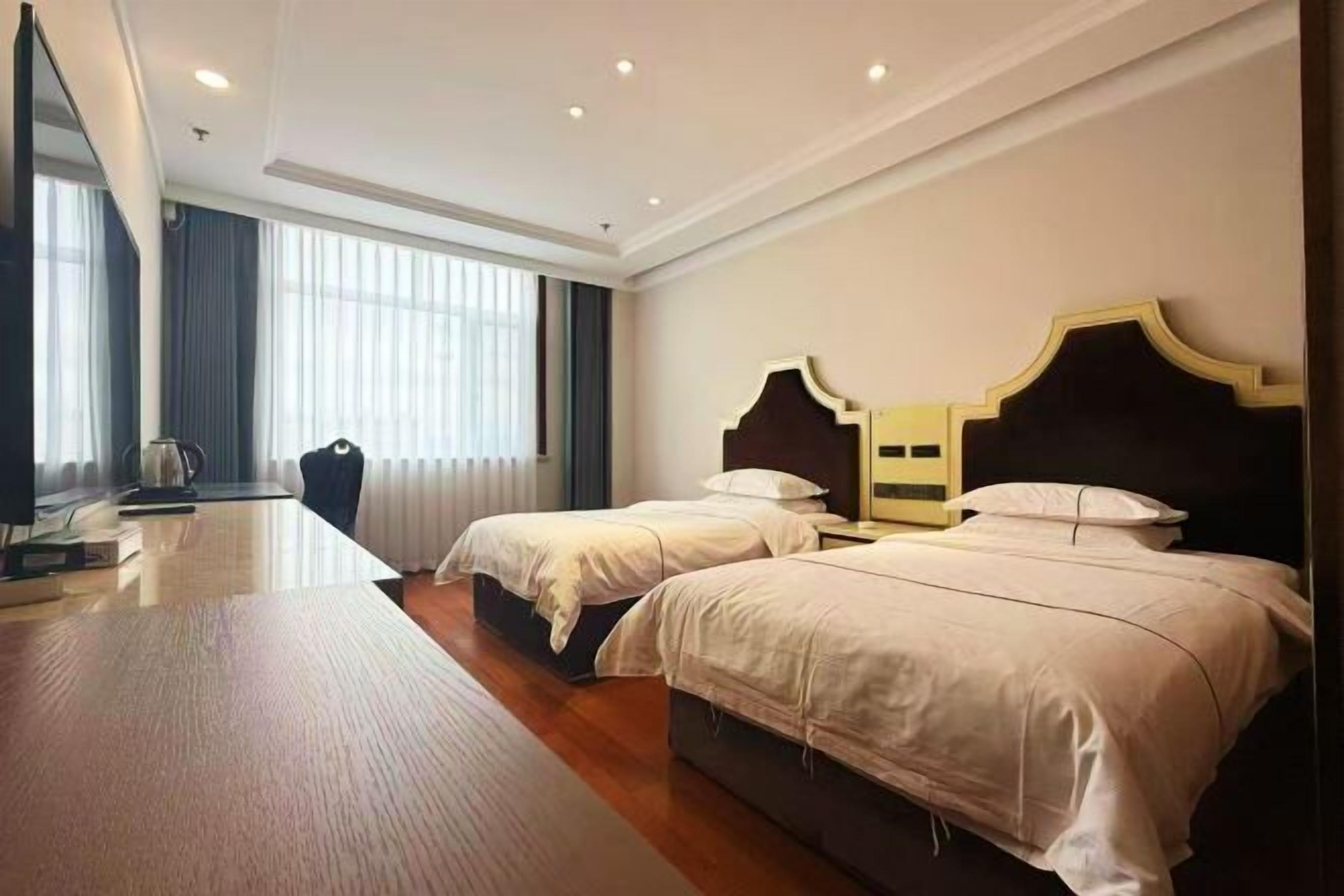 Une chambre d’hôtel avec deux lits, un bureau et une grande fenêtre.