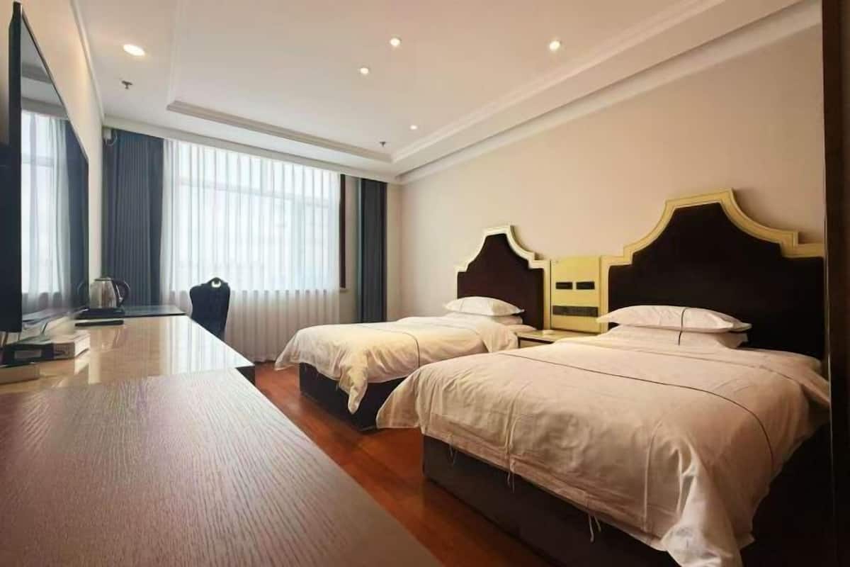 Une chambre d’hôtel avec deux lits, un bureau et une grande fenêtre.