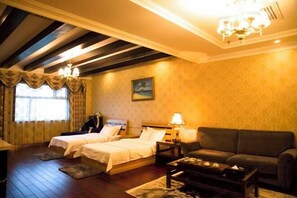 A hotel room with two beds, a sofa, a coffee table, and a painting on the wall.