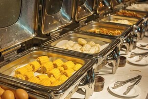 Un bufé con diversas opciones de comida, incluyendo maíz y otros platos.