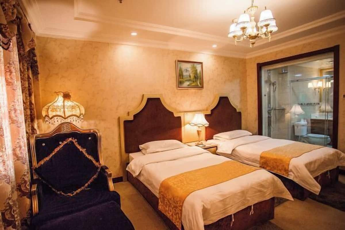 Una habitación de hotel con dos camas, una mesita de noche, una silla y una araña.