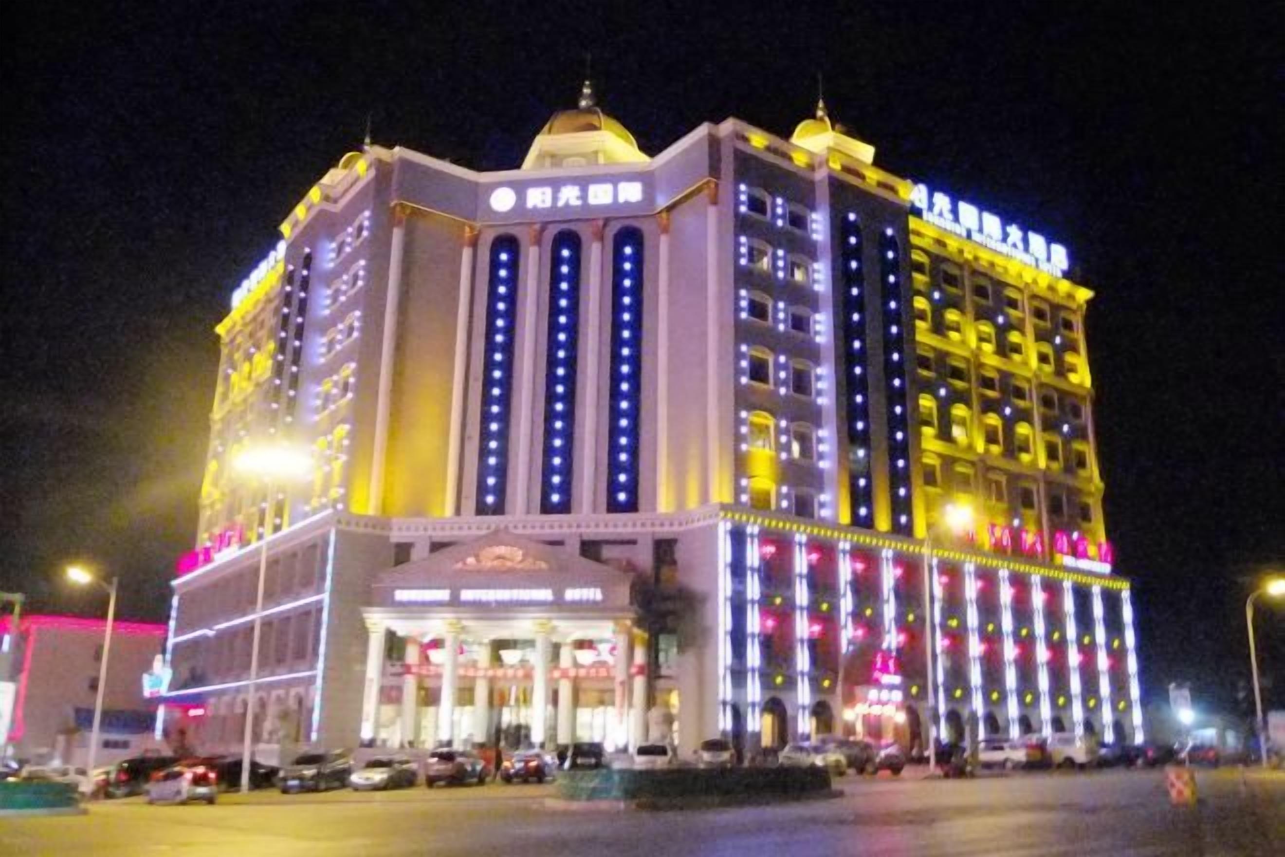 Un hôtel à plusieurs étages, doté d’une entrée imposante, d’une enseigne lumineuse et d’une série de fenêtres.