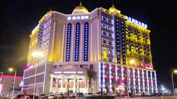 A multi-story hotel with a prominent entrance, illuminated signage, and a series of windows.