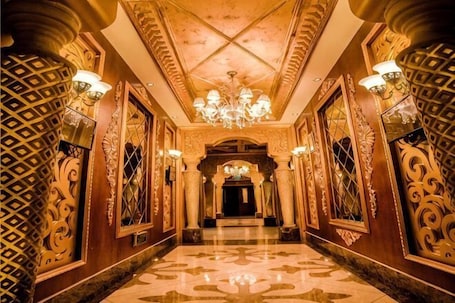 A grand hallway with ornate columns, chandeliers, and a patterned floor.. sunshine international hotel
