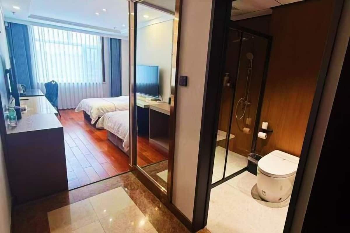 Una habitación de hotel con cama, escritorio, ducha y retrete.