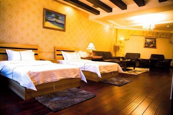 A hotel room with two beds, a wooden floor, and a painting on the wall.