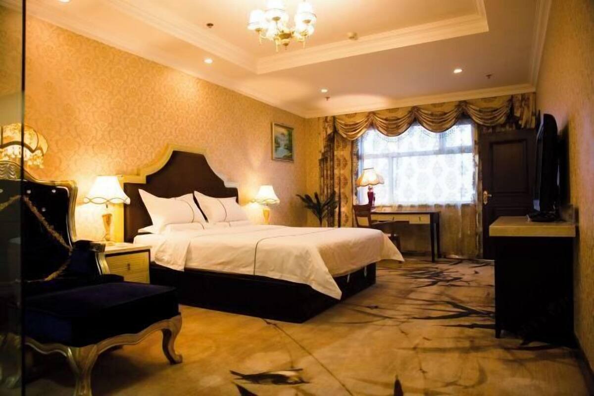 Una habitación de hotel con una cama grande, dos mesitas de noche con lámparas, un escritorio, una silla y un televisor.