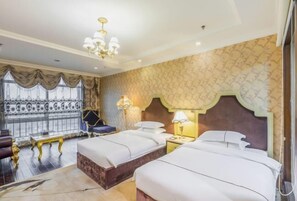Hotelkamer met twee bedden, een kroonluchter, behang met patroon en uitzicht door een raam met gordijnen.