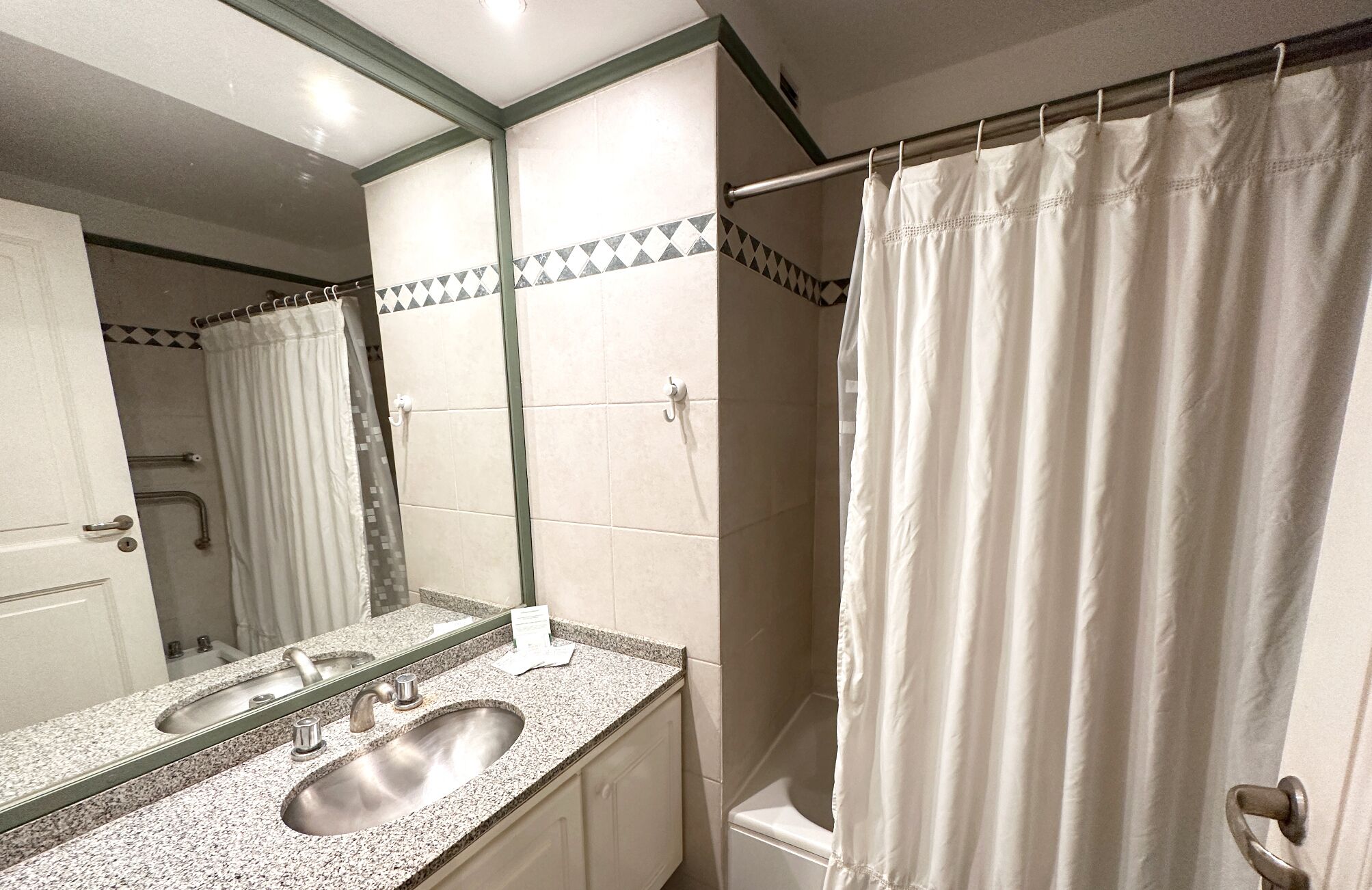 Un baño con lavamanos, espejo y cortina de ducha.
