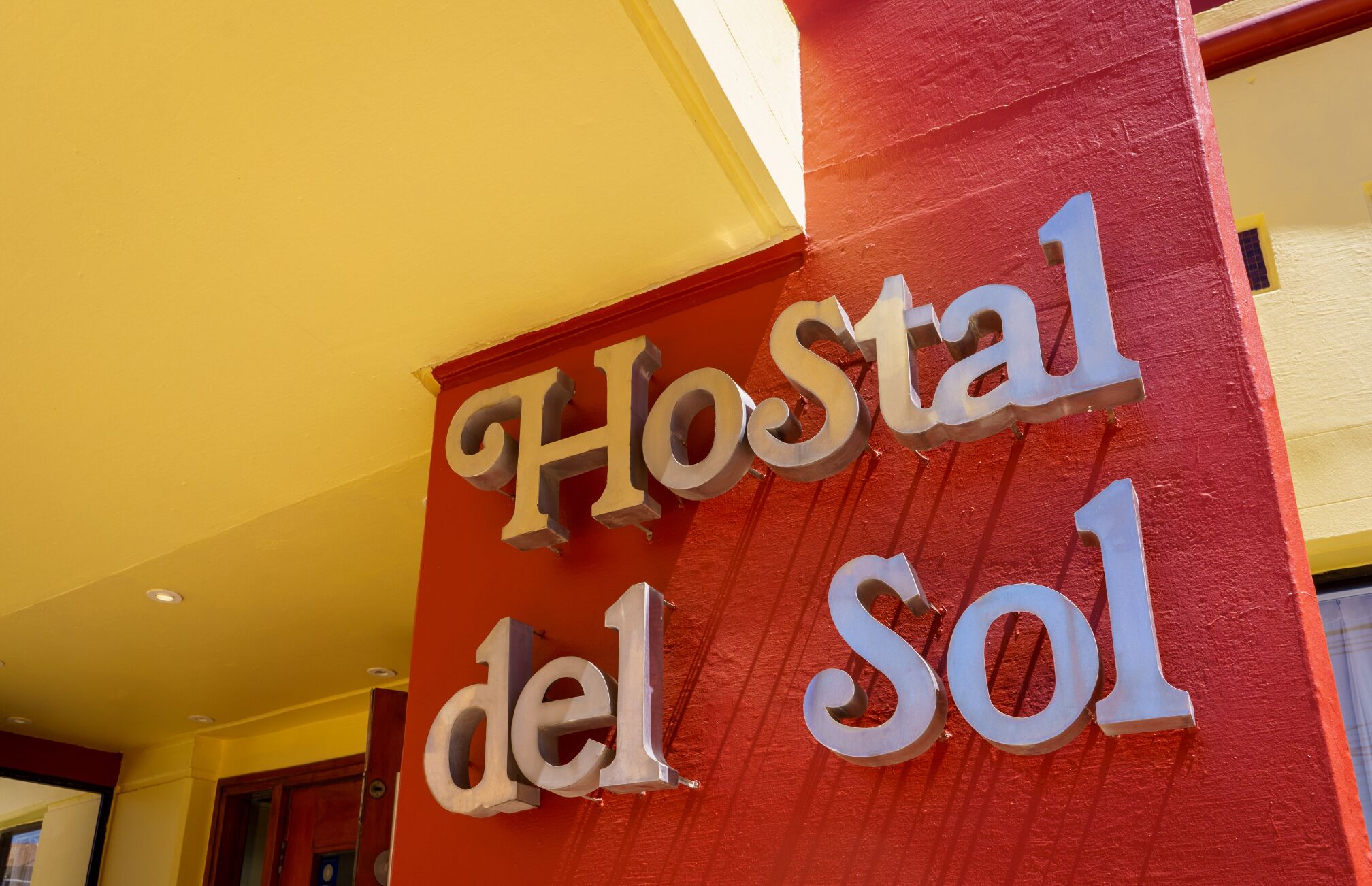 Une enseigne avec l’inscription « Hostal del Sol » sur un fond rouge.