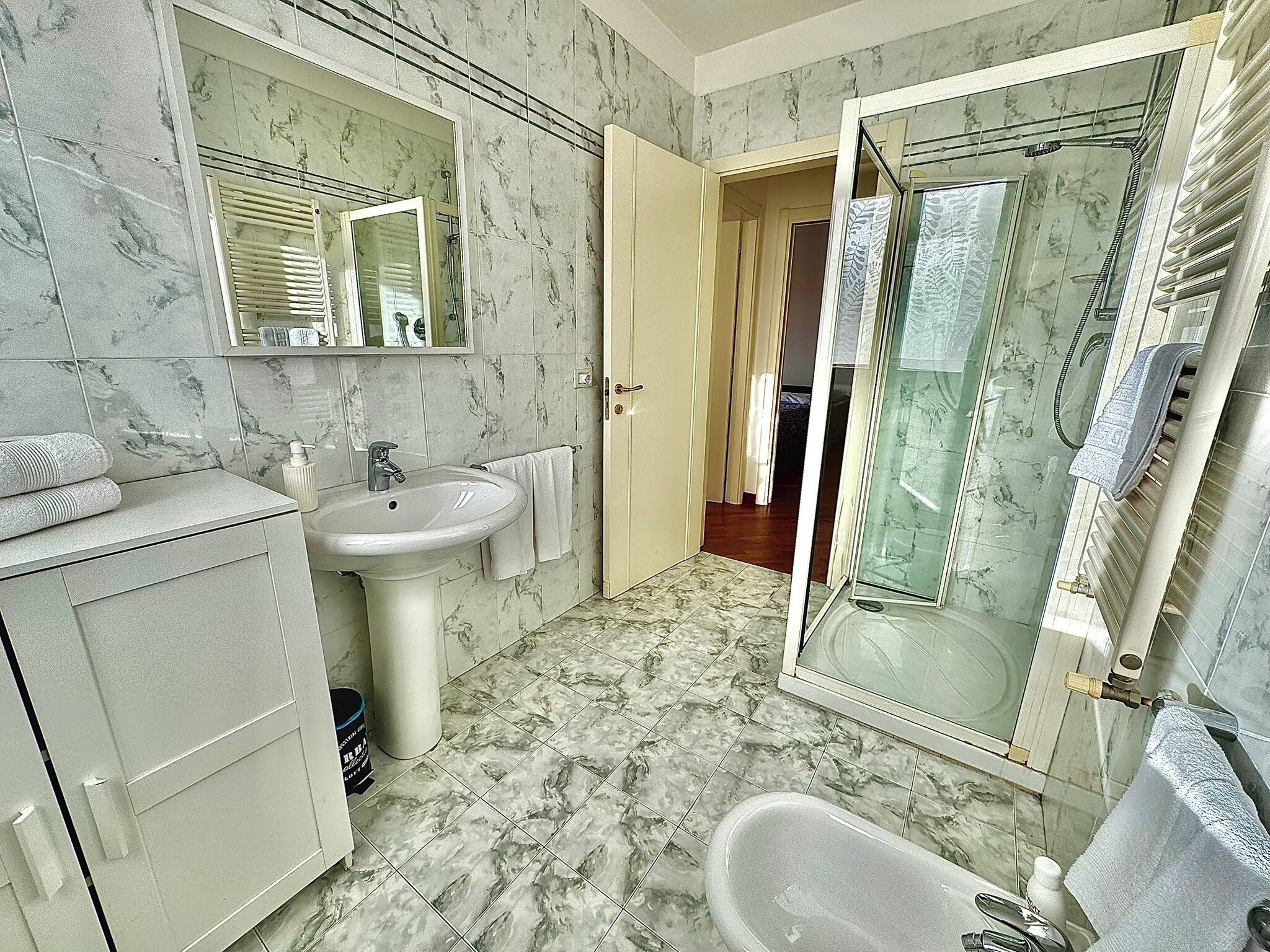A bathroom with a marble floor, a sink, a bathtub, and a shower area.