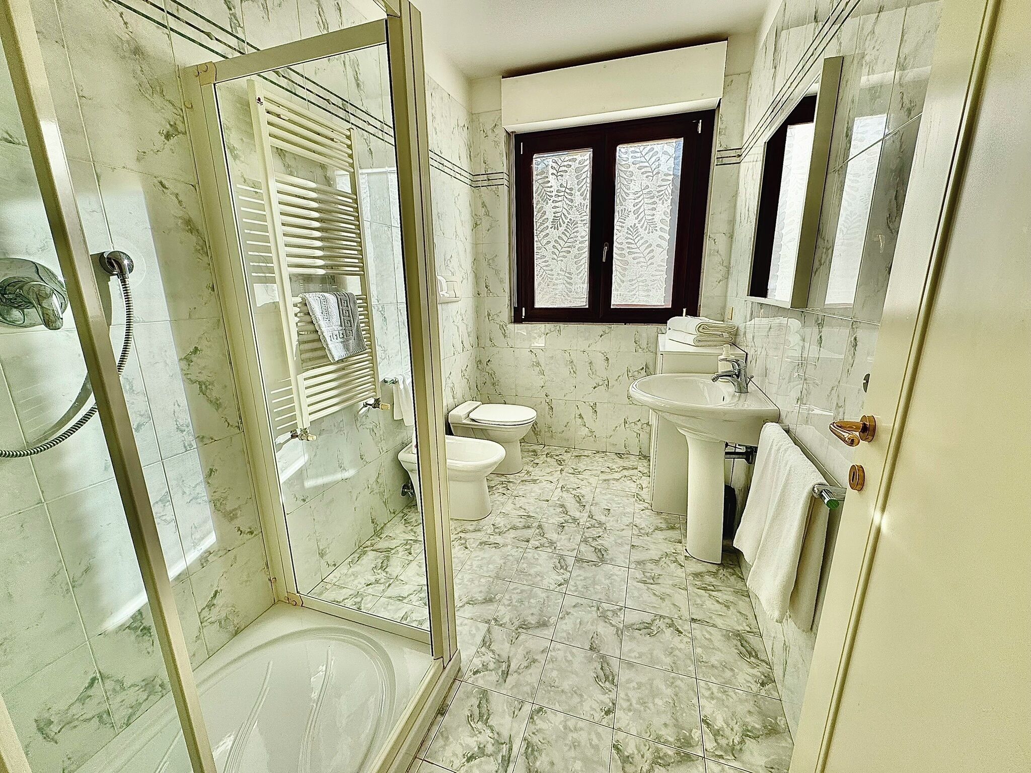 Une salle de bain avec une douche, des toilettes, un lavabo et une fenêtre.
