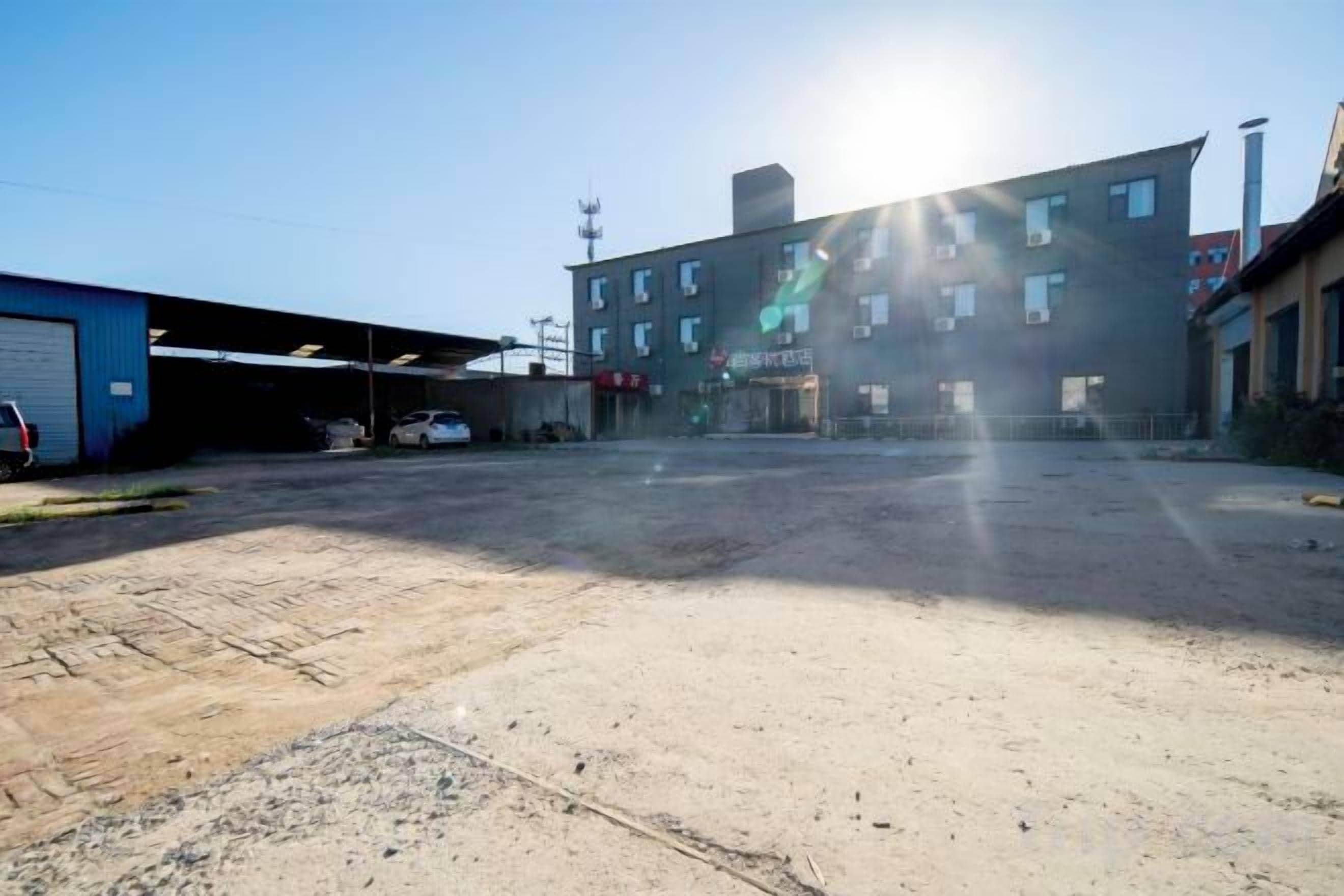 An industrial area with a large open space, buildings, and a clear sky.