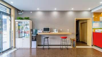 A modern kitchen area with a counter, stools, and a refrigerator.