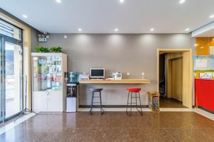 Un espace cuisine moderne avec un comptoir, des tabourets et un réfrigérateur.