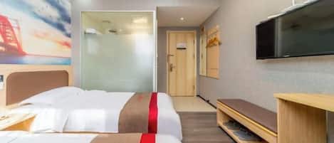 A hotel room with two beds, a TV, a desk, and a bookshelf.